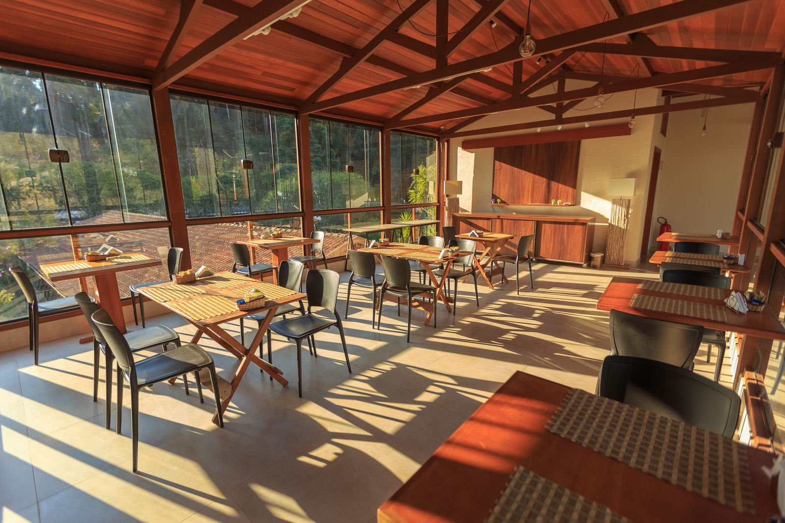 A bright and inviting indoor dining space featuring wooden tables and chairs with natural sunlight streaming in.